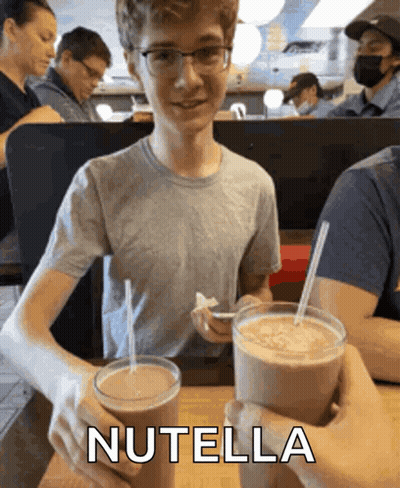 Boy Holding Two Milkshakes With Nutella GIF