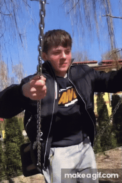 Boy In Black Jacket And An T-Shirt Swinging On Chain GIF