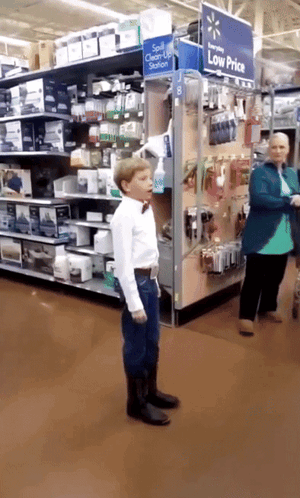 Boy In Bow Tie Standing Before Low Price Sign GIF
