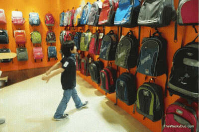 Boy In Front Of Wall Of Backpacks With Explorer GIF