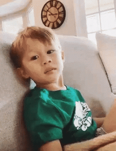 Boy In Green Shirt Sitting On Couch With Clock GIF