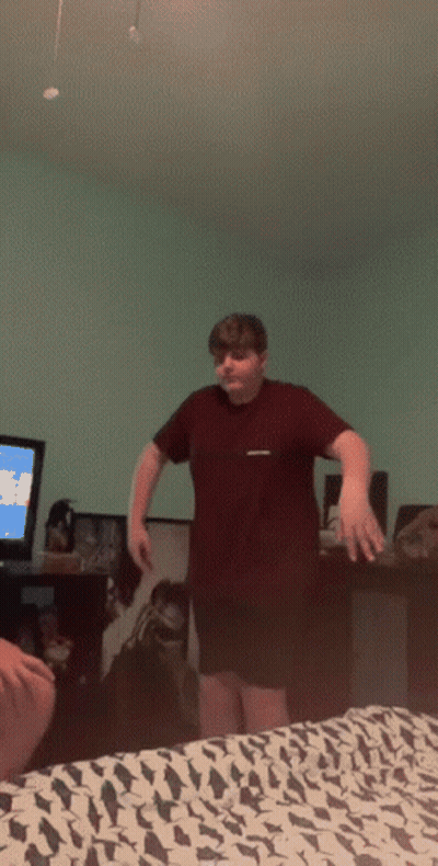 Boy In Maroon Shirt Standing In Front Of TV GIF