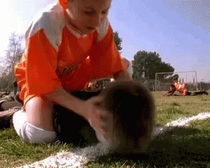 Boy In Orange Shirt Kneeling On Soccer Field GIF