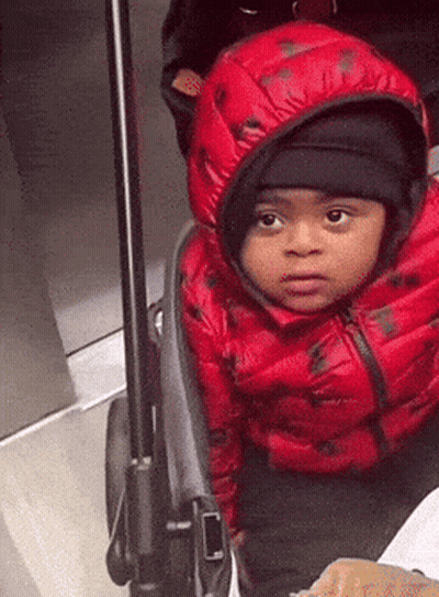 Boy In Red Jacket And Black Hat In Stroller GIF