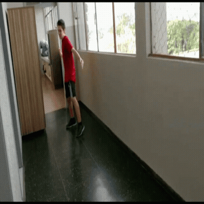 Boy In Red Shirt And Black Shorts Standing In Hallway GIF