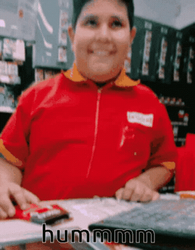 Boy In Red Shirt Sitting At Table Saying Hummm GIF