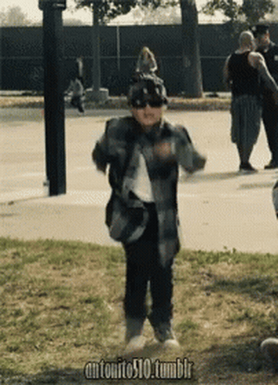 Boy In Sunglasses And Hat Dancing On Sidewalk GIF