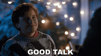 Boy In Sweater Says Good Talk Beside Christmas Lights GIF