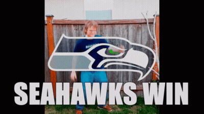 Boy Standing In Front Of Seahawks Logo GIF