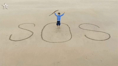Boy Standing On Beach With SOS In Sand GIF