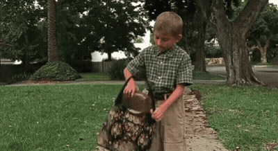 Boy Standing On Sidewalk Holding Bag GIF