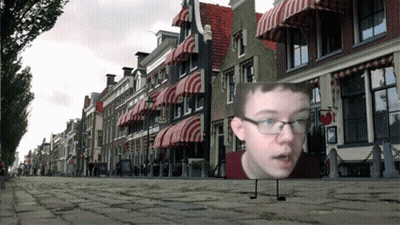 Boy With Glasses In Front Of Buildings GIF