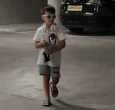 Boy With Headphones And Sunglasses Walking In Parking Garage GIF