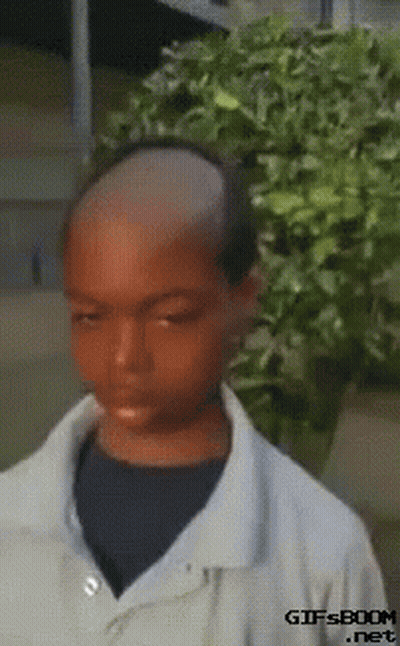 Boy With Shaved Head In Front Of Bush GIF