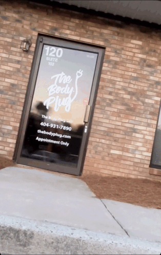 Brick Building With Glass Door Saying The Body Plug GIF