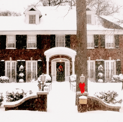 Brick House Covered In Snow With Red Bow On Door GIF