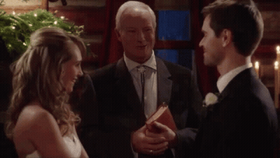 Bride and Groom Smiling at Wedding With Priest Holding Bible