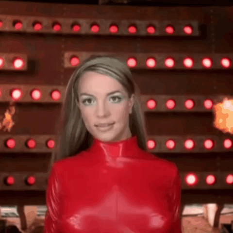 Britney Spears Is Wearing A Red Latex Outfit In Front Of A Wall Of Lights . GIF