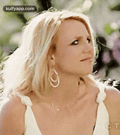 Britney Spears Is Wearing A White Dress And Earrings And Looking At The Camera . GIF