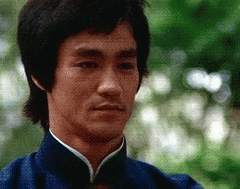 Bruce Lee Is Wearing A Blue Shirt With A White Collar GIF