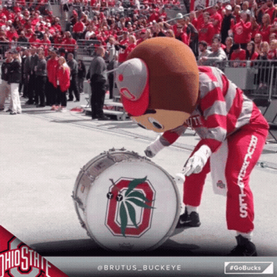 Brutus Buckeye Mascot Playing A Drum In Front Of A Crowd Of People GIF
