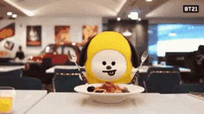 BT21 Stuffed Animal At Table With Food And Sign GIF