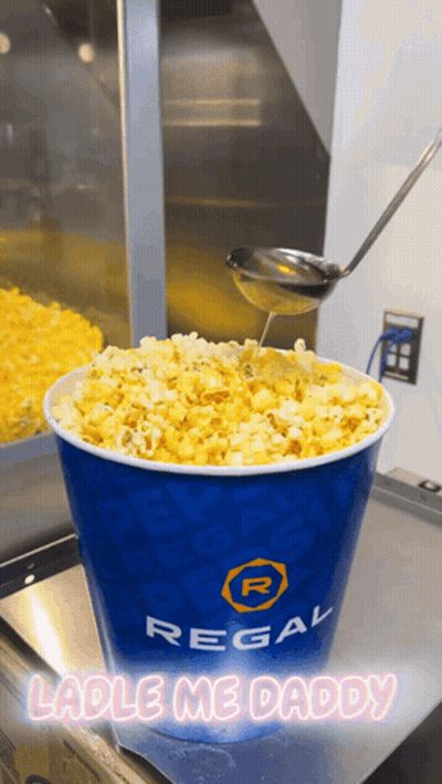 Bucket Of Regal Popcorn Being Poured With Spoon GIF