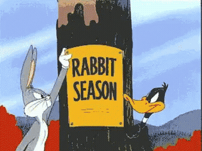 Bugs Bunny And Daffy Duck Are Holding A Sign That Says Rabbit Season GIF