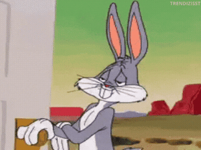 bugs bunny from looney tunes is standing in front of a door and looking at the camera .