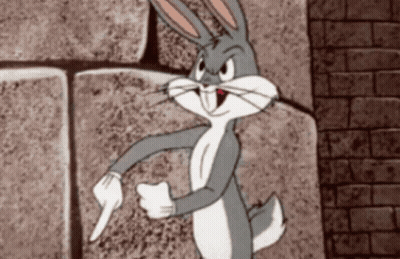 Bugs Bunny Is Standing In Front Of A Brick Wall Pointing GIF