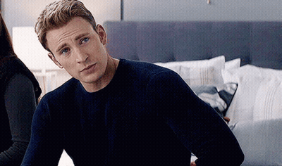 Captain America Is Wearing A Blue Sweater And Sitting On A Bed . GIF