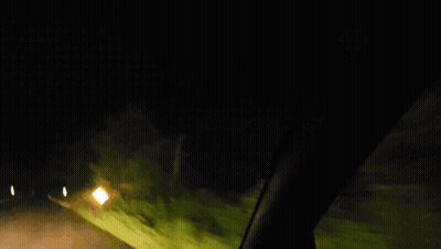 Car Driving Down Road At Night With Yellow Sign GIF