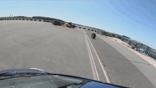 Car Driving Down Road With Tire On Side GIF