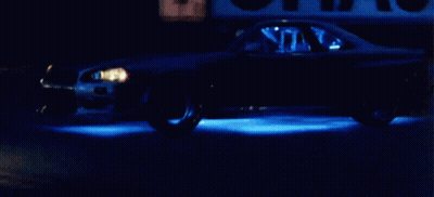 Car Driving Down Street At Night With Blue Lights GIF