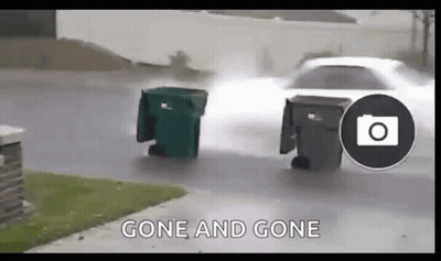 Car Driving Down Street Next To Trash Can In Rain GIF