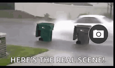 Car Driving Down Street Next To Two Garbage Cans In Rain GIF