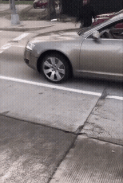 Car Driving Down Street With Person In Background GIF