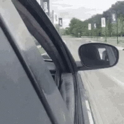 Car Driving Down Street With Rear View Mirror GIF