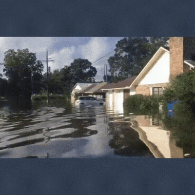 Car Floating in Flooded Street in Front of House