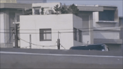 Car Parked By White Building With Rooftop Garden GIF