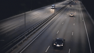 Cars Are Driving Down A Highway At Night And One Of Them Is A Yellow Car GIF