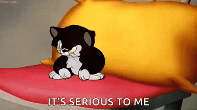 Cartoon Cat Sitting On Bed With Yellow Pillow GIF