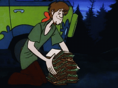 Cartoon Character Holding Sandwiches In Front Of Scooby Doo Vehicle GIF