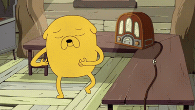 Cartoon Character Standing Next To Radio On Wooden Table GIF