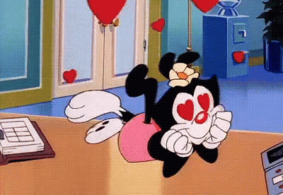Cartoon Character With Hearts In Eyes Sitting On Desk GIF