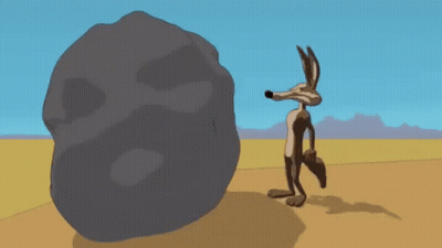 Cartoon Coyote Beside Large Rock In Desert GIF