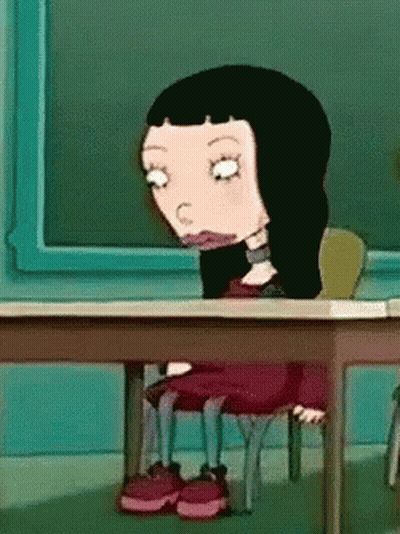 Cartoon Girl With Black Hair At Desk In Front Of Blackboard GIF