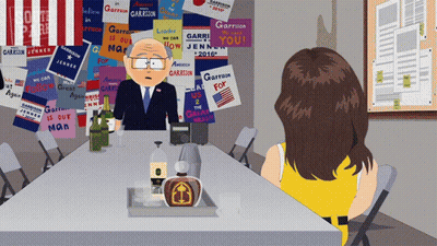 Cartoon Man Sitting At Table With Sign Garrison GIF