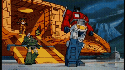 Cartoon Robot Optimus Prime Standing In Front Of Building GIF