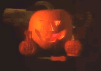 Carved Pumpkin Lit Up In Dark Surrounded By Pumpkins GIF
